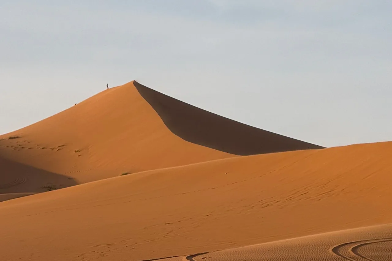 A curved orange dune crest against a clear blue sky